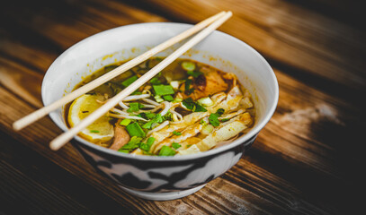 Wall Mural - Spicy asian Korean kuksi soup in bowl on wooden table background