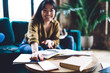 © BullRun - Cheerful young ethnic woman with books at home