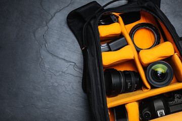 Wall Mural - professional photography equipment in backpack on slate table, top view. space for text