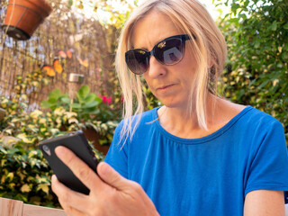 Poster - Closeup shot of a blonde woman in sunglasses looking at the phone