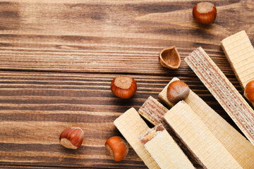 Poster - Wafer sticks with hazelnuts on brown wooden background