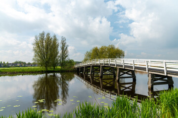 Sticker - white wooden bridge across a calm canal in country landscape