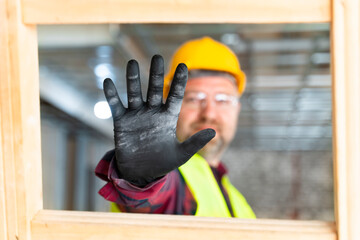 Man wearing personal protective equipment with hand up to Stop