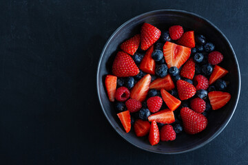 Wall Mural - Fresh berries on dark plate on table