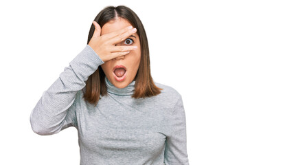 Canvas Print - Young beautiful woman wearing casual turtleneck sweater peeking in shock covering face and eyes with hand, looking through fingers with embarrassed expression.