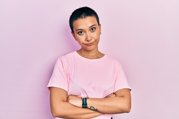 Poster - Beautiful hispanic woman with short hair wearing casual pink t shirt skeptic and nervous, disapproving expression on face with crossed arms. negative person.