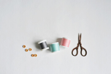 Wall Mural - Spool threads, wooden buttons and small scissors on white background