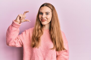 Sticker - Young blonde woman doing measure gesture with fingers smiling with a happy and cool smile on face. showing teeth.