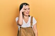 © Krakenimages.com - Middle age hispanic woman wearing casual clothes smiling happy doing ok sign with hand on eye looking through fingers