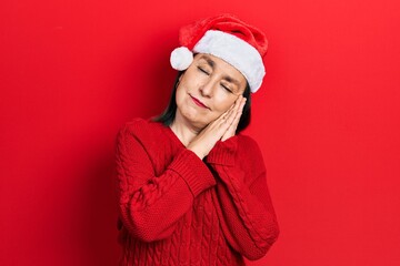 Canvas Print - Middle age hispanic woman wearing christmas hat sleeping tired dreaming and posing with hands together while smiling with closed eyes.