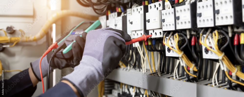 Electrician engineer tests electrical installations and wires on relay protection system. Adjustment of scheme of automation and control of electrical equipment. - obrazy, fototapety, plakaty 