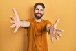 © Krakenimages.com - Caucasian man with beard wearing casual yellow t shirt looking at the camera smiling with open arms for hug. cheerful expression embracing happiness.