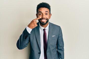 Poster - Handsome hispanic man with beard wearing business suit and tie pointing with hand finger to face and nose, smiling cheerful. beauty concept