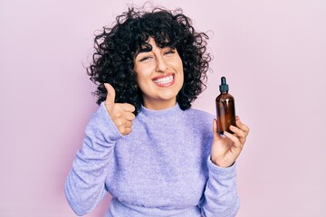 Sticker - Young middle east woman using night serum smiling happy and positive, thumb up doing excellent and approval sign