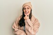 © Krakenimages.com - Young hispanic woman wearing wool sweater and winter hat looking confident at the camera smiling with crossed arms and hand raised on chin. thinking positive.