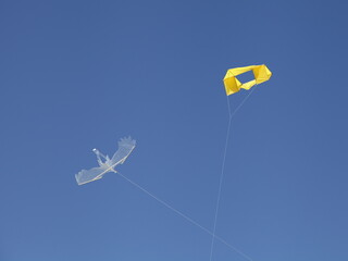 Two toy kites gliding in clear blue sky at Sunny day