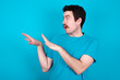 © Jihan - Displeased young handsome Caucasian man with moustache wearing blue t-shirt against blue background keeps hands towards empty space and asks not come closer sees something unpleasant