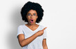 © Krakenimages.com - Young african american woman wearing casual white t shirt surprised pointing with finger to the side, open mouth amazed expression.