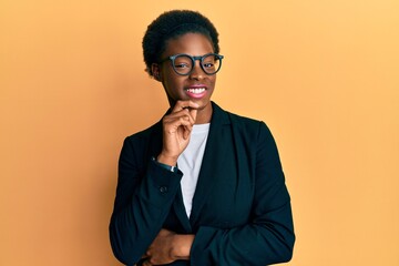 Wall Mural - Young african american girl wearing business jacket and glasses smiling looking confident at the camera with crossed arms and hand on chin. thinking positive.