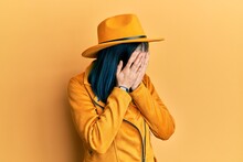 Young Modern Girl Wearing Yellow Hat And Leather Jacket With Sad Expression Covering Face With Hands While Crying. Depression Concept.