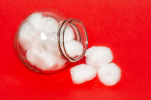 Cotton Balls Jar Isolated On A Red Background. Fluffy Clean White Cotton Balls Stored In A Glass Bottle.