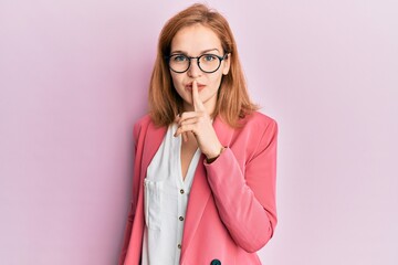 Wall Mural - Young caucasian woman wearing business style and glasses asking to be quiet with finger on lips. silence and secret concept.