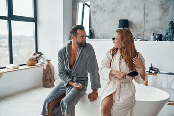 Wall Mural - Couple in bathrobes smiling and cleaning teeth while doing morning routine