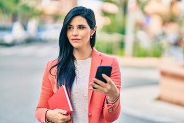 Wall Mural - Young beautiful businesswoman with serious expression using smartphone at the city.