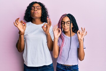 Poster - Beautiful african american mother and daughter wearing casual clothes and glasses relaxed and smiling with eyes closed doing meditation gesture with fingers. yoga concept.