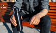 Close-up of male hands, holding steel reusable thermo water bottle of black.