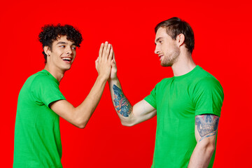 two friends in green t-shirts communication red background studio