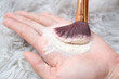 Close up woman holding talc make up and brush on carpet background, beauty concept.