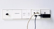 Close up switch panel with light switch, internet connection, audio, HDMI and AC outlet plug installed on white wall with copy space. Control device and Technology concept.