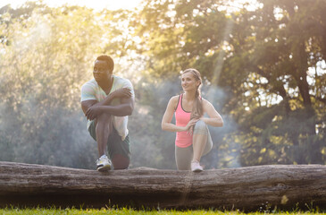 Black Caucasian couple stretching after exercise on tree trunk