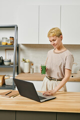 Sticker - A person using laptop by kitchen table against shelves and cabinets