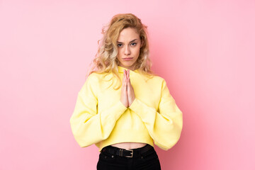 Poster - Young blonde woman wearing a sweatshirt isolated on pink background keeps palm together. Person asks for something