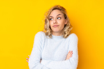 Poster - Young blonde woman isolated on yellow background making doubts gesture while lifting the shoulders