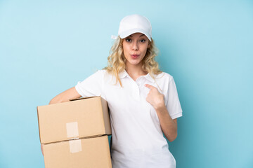 Young delivery woman isolated on blue background with surprise facial expression