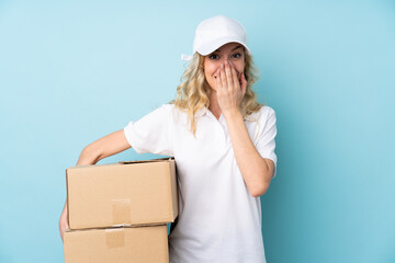 Canvas Print - Young delivery woman isolated on blue background with surprise facial expression