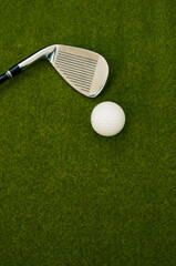 Wall Mural - Vertical shot of a golf club and a ball on the grass with a copy space