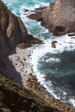 The Ocean Crashing Into A Beach And Cliff Face In Big Sur California