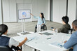 © Seventyfour - Wide angle portrait of successful businesswoman in wheelchair leading team meeting and pointing at digital whiteboard in office, copy space