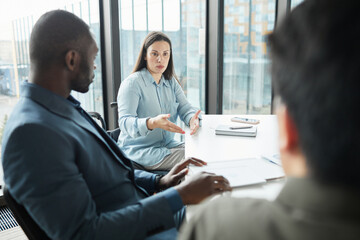 Portrait of successful disabled businesswoman in wheelchair leading meeting with diverse business team in office