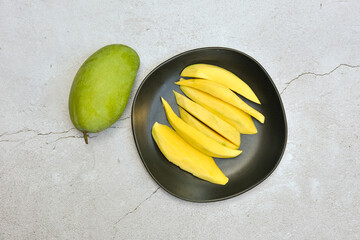 Green mango and ready to eat on black dish on grungy cement floor background, Group of fresh mangoes organic with sour and high vitamin C fruit for healthy with copy space, ready to add text