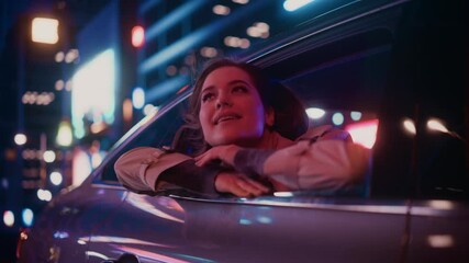 Wall Mural - Excited Young Female is Sitting on Backseat of a Car, Commuting Home at Night. Looking Out of the Window with Amazement of How Beautiful is the City Street with Working Neon Signs. Cinematic Footage.