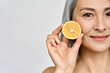 Beauty. Closeup portrait of middle aged beautiful Asian 50s woman with perfect natural makeup holding citrus juicy lemon fruit. Vitamin C cosmetics whitening treatment advertising concept. Copy space.