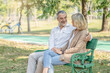 © Pormezz - Elderly couple lifestyle concept. Husband embrace wife and sit on seat in the park relax on retirement life.