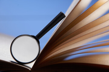 Book and a magnifying glass on a blue background