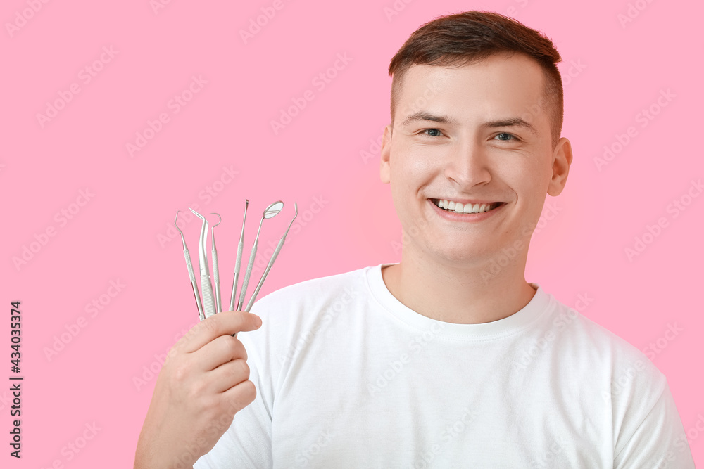 Young man with dental tools on color background