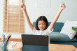 © sorrapongs - Happy Asian little girl raise hand is learning online with  tablet